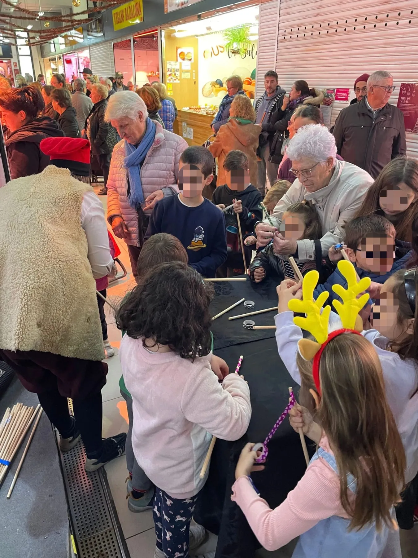 Infants decorant els seus bastons en una taula amb cintes i materials durant el taller, en un mercat